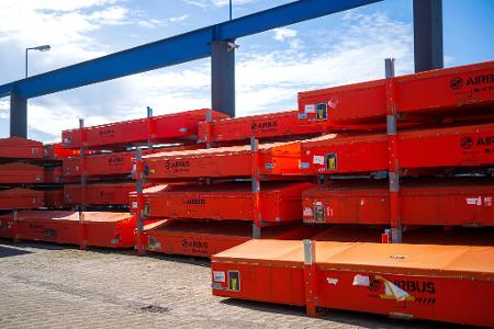 Vor der Werkhalle warten beschädigte Fahrzeugteile auf die Reparatur.