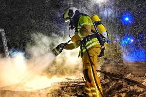 © Feuerwehr Dresden
Symbolbild: Eine Einsatzkräfte löscht die Glutnester einer abgebrannten Gartenlaube ab.