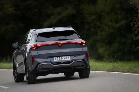 Cupra Terramar 1,5eTSI auf Landstraße, Rückansicht, graues SUV, modernes Design, bewaldeter Hintergrund.