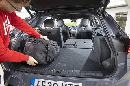 Ein Mann lädt eine schwarze Tasche in den Kofferraum eines Cupra Terramar 1,5 eTSI. Die Rücksitze sind umgeklappt, der Innenraum und das Cockpit sind sichtbar.