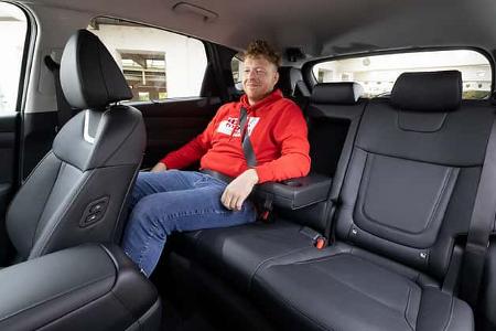 Innenraumaufnahme des Hyundai Tucson 1.6 T-GDI mit einer Person auf der Rücksitzbank. Die Aufnahme zeigt die Ledersitze und die Beinfreiheit im Fond.