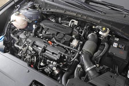 Detailaufnahme des Motorraums eines Hyundai Tucson 1.6 T-GDI. Der Turbo-Benzinmotor ist zentral im Bild zu sehen, umgeben von verschiedenen Motorkomponenten und Flüssigkeitsbehältern.
