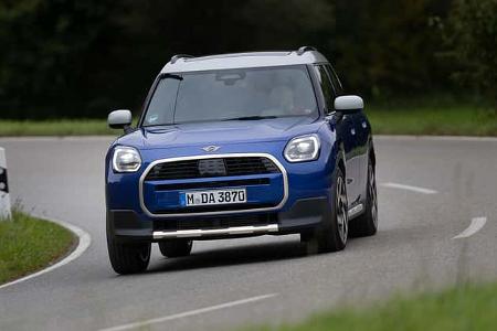 Blauer Mini Countryman C 2,0 fährt auf einer kurvigen Landstraße, Frontansicht, Tageslicht.