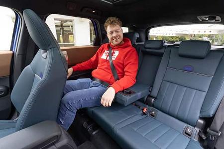 Innenraumaufnahme eines Mini Countryman C 2,0 mit einer Person auf der Rücksitzbank. Die Aufnahme zeigt die blauen Ledersitze und das Platzangebot im Fond.