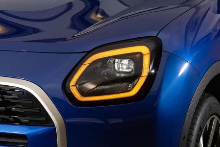Detailaufnahme des rechten LED-Scheinwerfers eines blauen Mini Countryman C 2,0. Die Aufnahme zeigt den Frontscheinwerfer mit markanter LED-Tagfahrlichtsignatur und einen Teil des Kühlergrills sowie des vorderen rechten Kotflügels.
