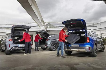 Drei SUVs – Cupra Terramar, Mini Countryman und Hyundai Tucson – stehen nebeneinander in einem Parkhaus. Die Heckklappen sind geöffnet, Personen laden Gepäckstücke in die Kofferräume.