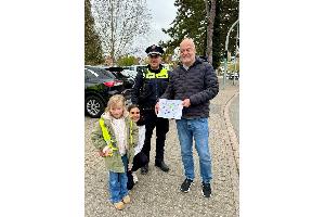Ein Mädchen der Kita Gabelsberger Straße überreicht einem Verkehrsteilnehmer ein selbstgemaltes Bild mit einer klaren Botschaft: Rücksicht im Straßenverkehr. Begleitet wird die Aktion u.a. von einer Erzieherin sowie dem Polizeibeamten PK Liedtke.