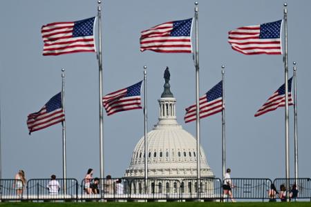 US-Fahnen wegen am Washington Monument. Im Hintergrund ist die Kuppel des US-Kapitols zu sehen.