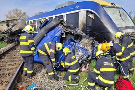 Feuerwehrleute arbeiten am Unglücksort, wo ein Personenzug und ein Lastwagen zusammengestoßen sind. Bei dem Unglück kam eine Person ums Leben, 21 Menschen wurden verletzt.