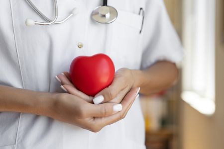 Ärztin hält sich ein kleines Herz vor die Brust