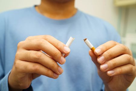 Junger Mann zerbricht eine Zigarette