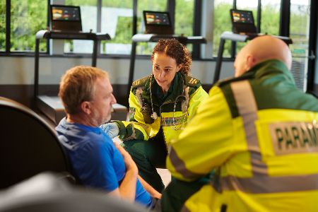 Mann auf Trage wird von zwei Rettungssanitätern versorgt