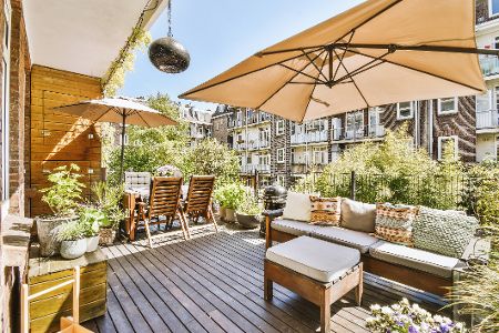 Balkon mit verschiedenen Möbeln, Sonnenschirm und Blumen