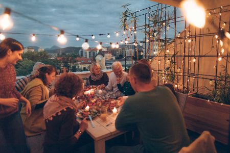 Gruppe von Menschen feiert abends auf dem Balkon
