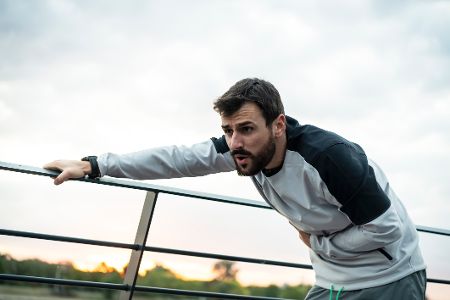 Mann beim Joggen macht erschöpft Pause