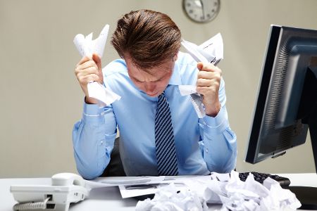 Mann im Büro knüllt verzweifelt Papier zusammen