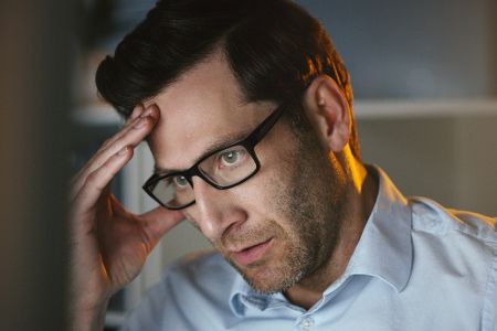 Mann mittleren Alters greift sich mit Konzentrationsproblemen an den Kopf