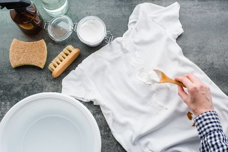 Weißes T-Shirt, das mit Natron, Bürste und Wasser gereinigt werden soll
