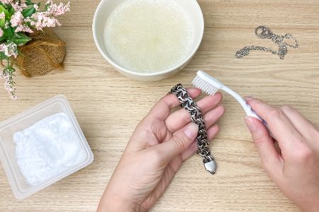 Frau reinigt Silberschmuck mit Natron