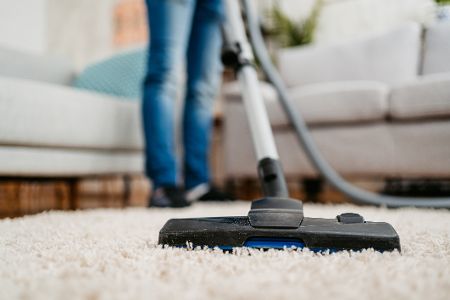 Person saugt Staub auf einem Teppich