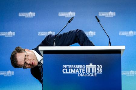 Umweltminister Carsten Schneider (SPD) beugt sich beim 17. Petersberger Klimadialog neben das Pult.