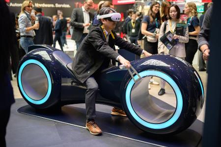 Durch eine Augmented-Reality-Brille schauend sitzt ein Gast auf einem fiktiven Gefährt bei der Industriemesse Hannover.