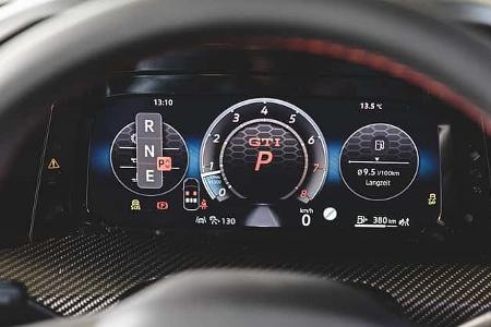Digitales Kombiinstrument des VW Golf GTI, fotografiert aus der Fahrerperspektive. Das Display zeigt Drehzahlmesser, Fahrstufenanzeige und Verbrauchsdaten.
