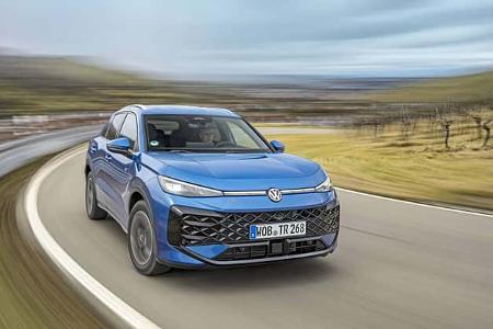 VW T-Roc eTSI auf Landstraße in Fahrt, blaues Kompakt-SUV, dynamische Kurvenfahrt, Frontansicht.