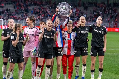 Bayern Münchens Spielerinnen jubeln nach dem Spiel gegen den 1. FC Union Berlin mit der Nachbildung einer Meisterschale über den Sieg.
