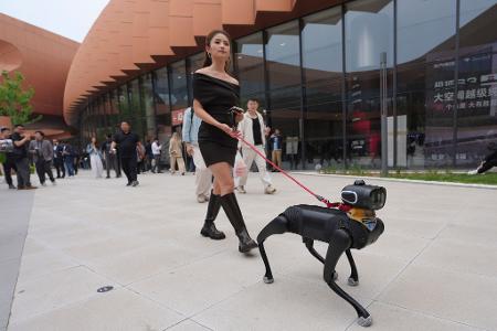 Hundesteuer gespart: Eine Frau geht mit einem Roboterhund während der Messe Auto China 2026 in Peking spazieren.