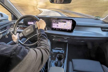Innenraumaufnahme eines Audi Q3 SUV TFSI quattro während der Fahrt, Blick aus Fahrersicht auf Lenkrad, Cockpit und zentrales Infotainment-Display mit Navigationskarte.