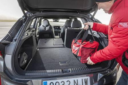 Der geöffnete Kofferraum eines Cupra Terramar 2.0TSI 4Drive mit umgeklappter Rückbank. Eine Person legt eine rote Tasche in den Laderaum.