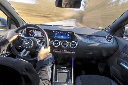 Innenraumaufnahme eines Mercedes GLA250 4Matic während der Fahrt, Blick über die Schulter des Fahrers auf das Cockpit und die Straße.