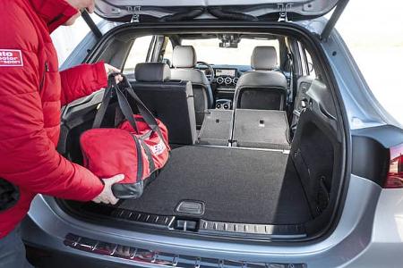 Der Kofferraum eines Mercedes GLA250 4Matic mit umgeklappter Rückbank. Eine Person legt eine rote Tasche in den Laderaum.