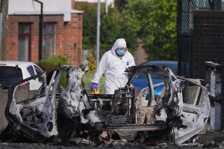 Nach einer Explosion vor einer Polizeistation steht ein Ermittler neben einem zerstörten Auto in Dunmurry, nahe Belfast in Nordirland. 
