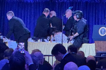 Geheimdienstmitarbeiter bringen US-Präsident Trump nach den Geräuschen von Schüssen während des White House Correspondents Dinner von der Bühne.