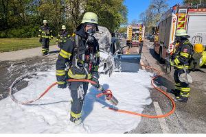 Einsatzkräfte der Feuerwehr München bei einem Pkw-Brand.