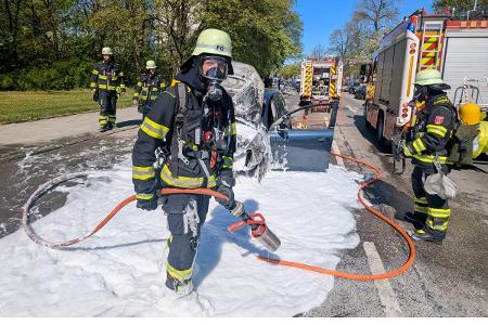 Einsatzkräfte der Feuerwehr München bei einem Pkw-Brand.