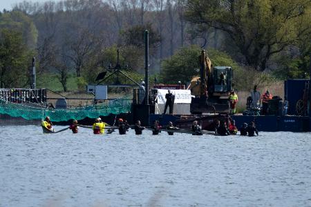 Helfer versuchen den gestrandeten Wal aus dem flachen Wasser zu einem Transportschiff zu ziehen, das in der Fahrrinne wartet.