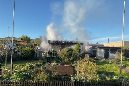 Das Bild zeigt Löscharbeiten an der vom Brand betroffenen Gartenlaube.