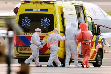 Sanitäter begleiteten eine Person mit Verdacht auf eine Hantavirus-Infektion auf dem Amsterdamer Flughafen zu einem Krankenwagen.