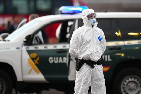 Die Sicherheitsvorkehrungen sind hoch: Ein Mitglied der Guardia Civil, das einen weißen Schutzanzug und Maske trägt, steht auf dem Hafengelände.