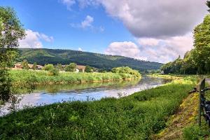 Panorama from the long-distance cycle path next to the Weser in Germany in the Weserbergland, with green banks and cloudy sky