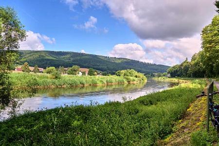 Panorama from the long-distance cycle path next to the Weser in Germany in the Weserbergland, with green banks and cloudy sky
