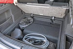 BMW X1 xDrive 30e Kofferraum mit geöffneter Bodenklappe und Ladekabel.