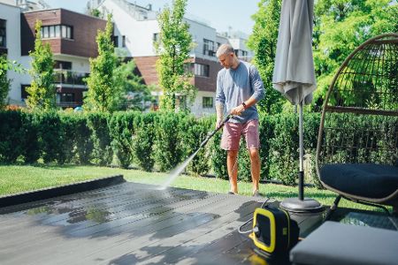Mann kärchert seine Terrasse
