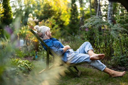 Frau entspannt im Garten im Liegestuhl