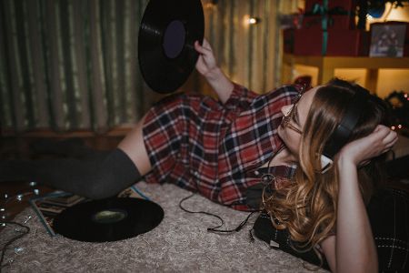 Junge Frau liegt gemütlich auf dem Boden und hört Schallplatten