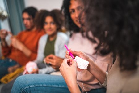 Gruppe junger Menschen sitzt zusammen und häkelt