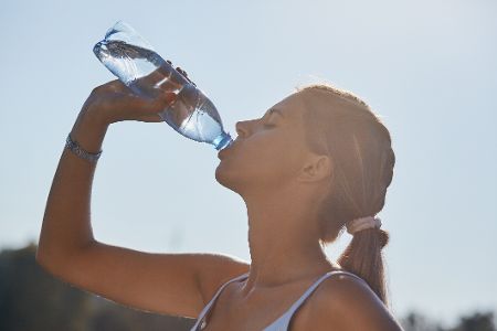 Frau im Sommer trinkt Wasser